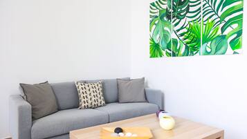 Una sala de estar moderna con un sofá gris, una mesa de centro de madera y una obra de arte en la pared.