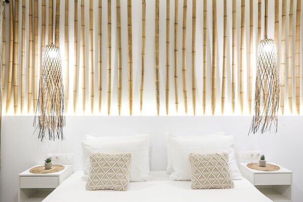A modern bedroom with a white bed, two nightstands, and a bamboo wall panel.