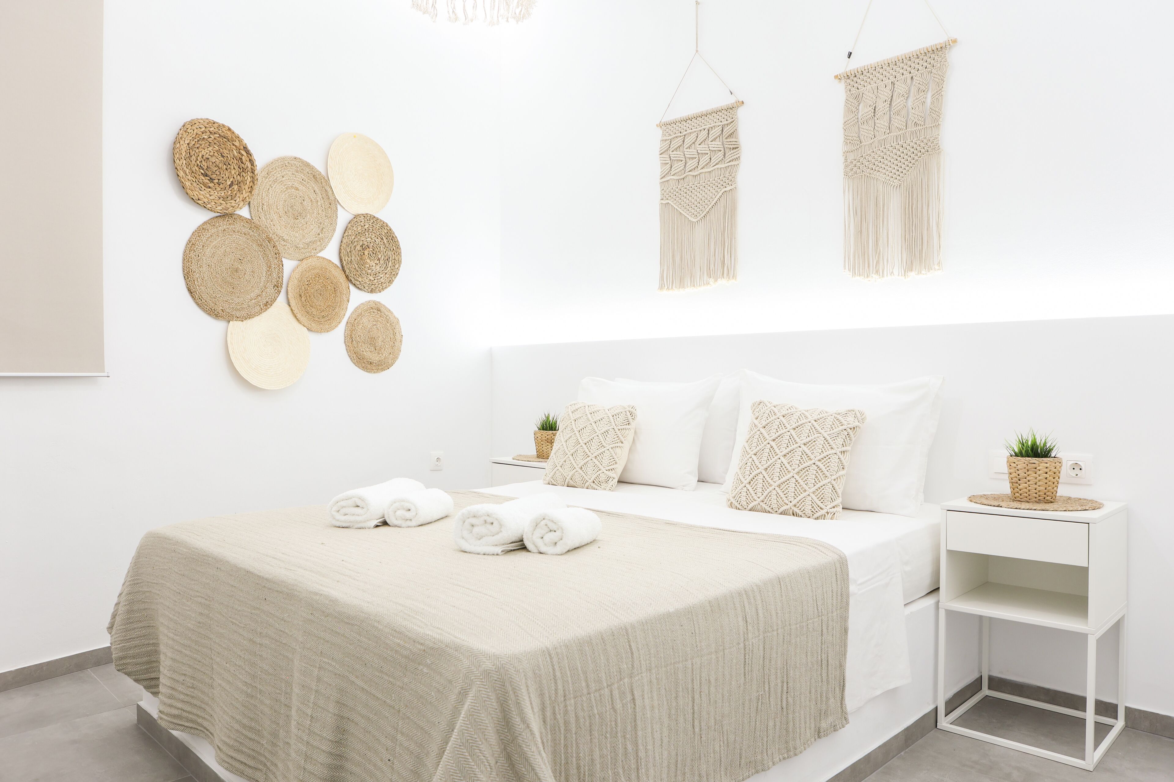 Un dormitorio minimalista con cama, mesitas de noche y decoración en la pared.