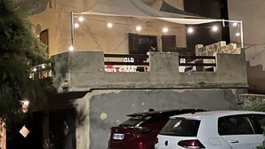 Ein Gebäude mit Balkon, Lichterketten und parkenden Autos.