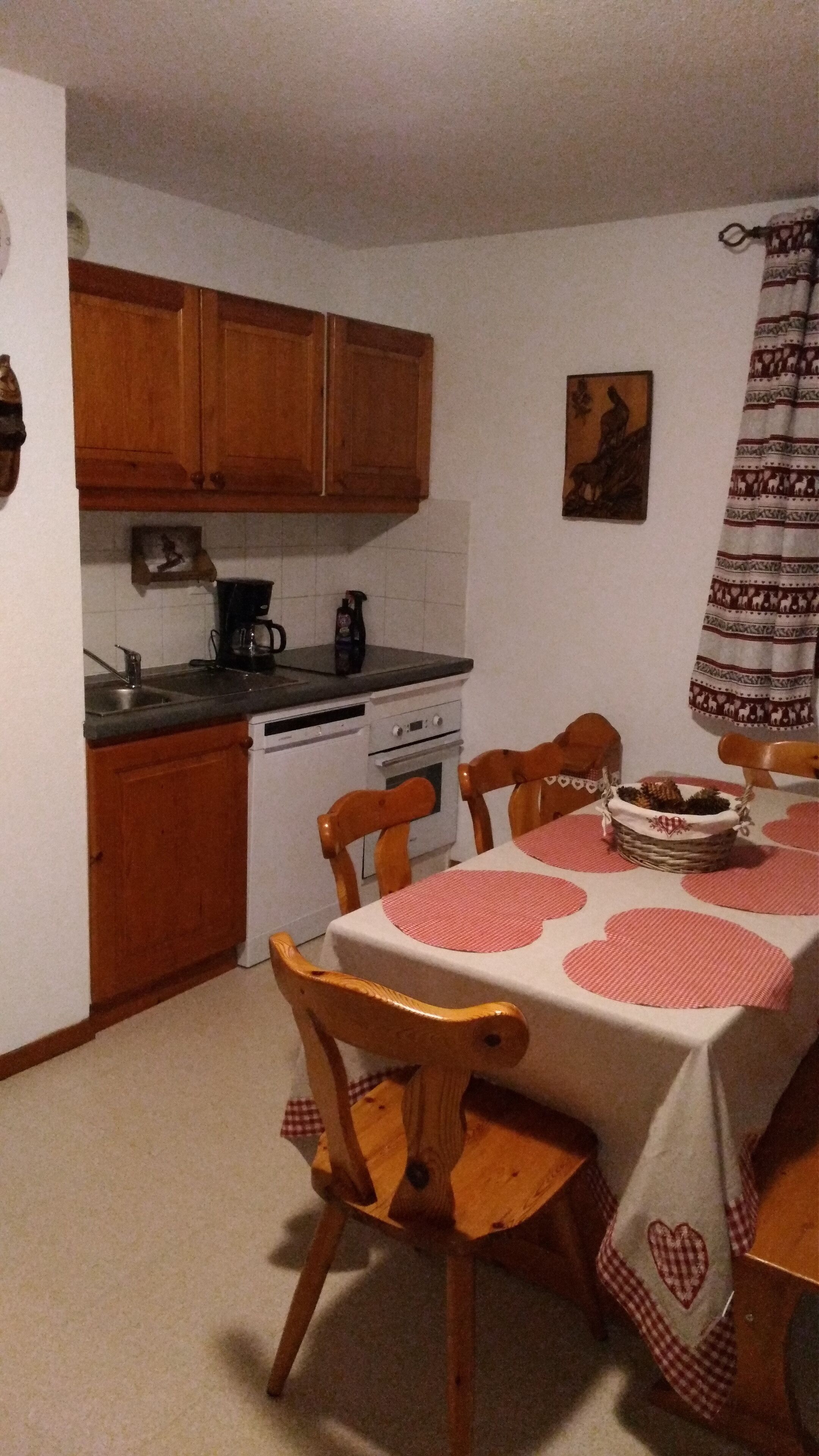 Une cuisine de taille réduite, avec des meubles de rangement en bois, une cuisinière et une table à manger avec des chaises.
