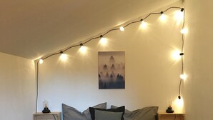 A bed with a pallet base, a string of lights, and a painting on the wall. - Waldhaus Neuleutasch, plenty of space to be outside, far away from the hustle and bustle (Leutasch)