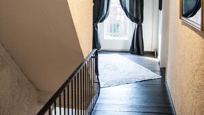 A narrow hallway with a wooden floor, a black railing, and a hanging plant. - Bauernhaus am Sallingbach (Rohr in Niederbayern)
