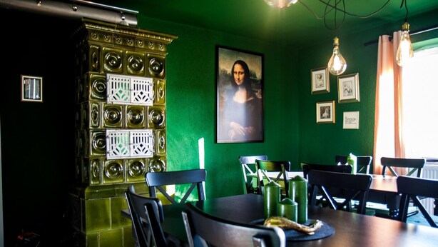 A dining area with a green wall, a large painting of the Mona Lisa, and a decorative wall unit with circular patterns. - Bauernhaus am Sallingbach (Rohr in Niederbayern)