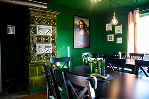 Un espace repas agrémenté d’un mur vert, d’un grand tableau représentant la Joconde et d’un meuble mural décoratif orné de motifs circulaires.