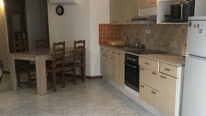 Eine Küche mit Esstisch und Stühlen, einer Mikrowelle, einem Backofen und einem Kühlschrank.