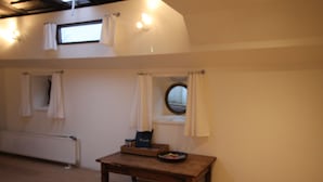Een kamer met een houten tafel, een radiator en een raam met gordijnen.