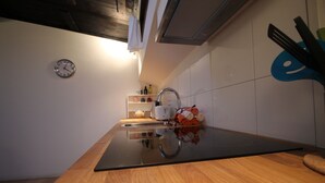Een moderne keuken met een houten aanrecht, een roestvrijstalen spoelbak en een klok aan de muur.