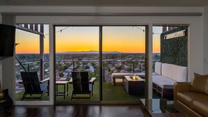 A spacious balcony with a glass door, a fire pit, and a sofa.