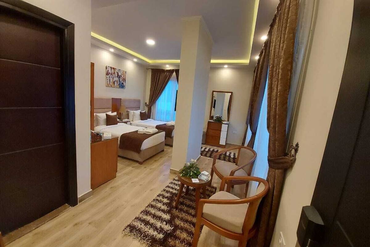 A hotel room with a bed, a desk, a chair, and a small table.