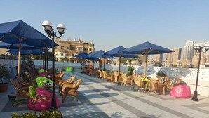 A rooftop terrace with outdoor seating, umbrellas, and potted plants. - Jewel Zamalek Hotel (Cairo)