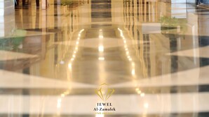 A hotel corridor with a polished floor, wooden benches, potted plants, and a series of doors along the walls. - Jewel Zamalek Hotel (Cairo)