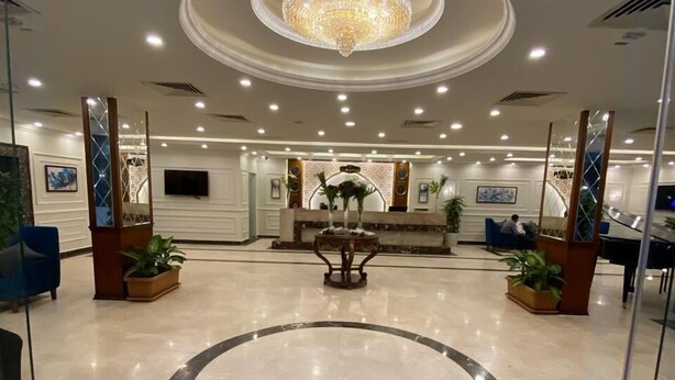 A hotel lobby with a central reception desk, a chandelier, and potted plants. - Jewel Zamalek Hotel (Cairo)
