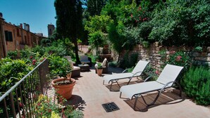 Eine Terrasse im Freien mit Liegestühlen, einem kleinen Tisch und Topfpflanzen.