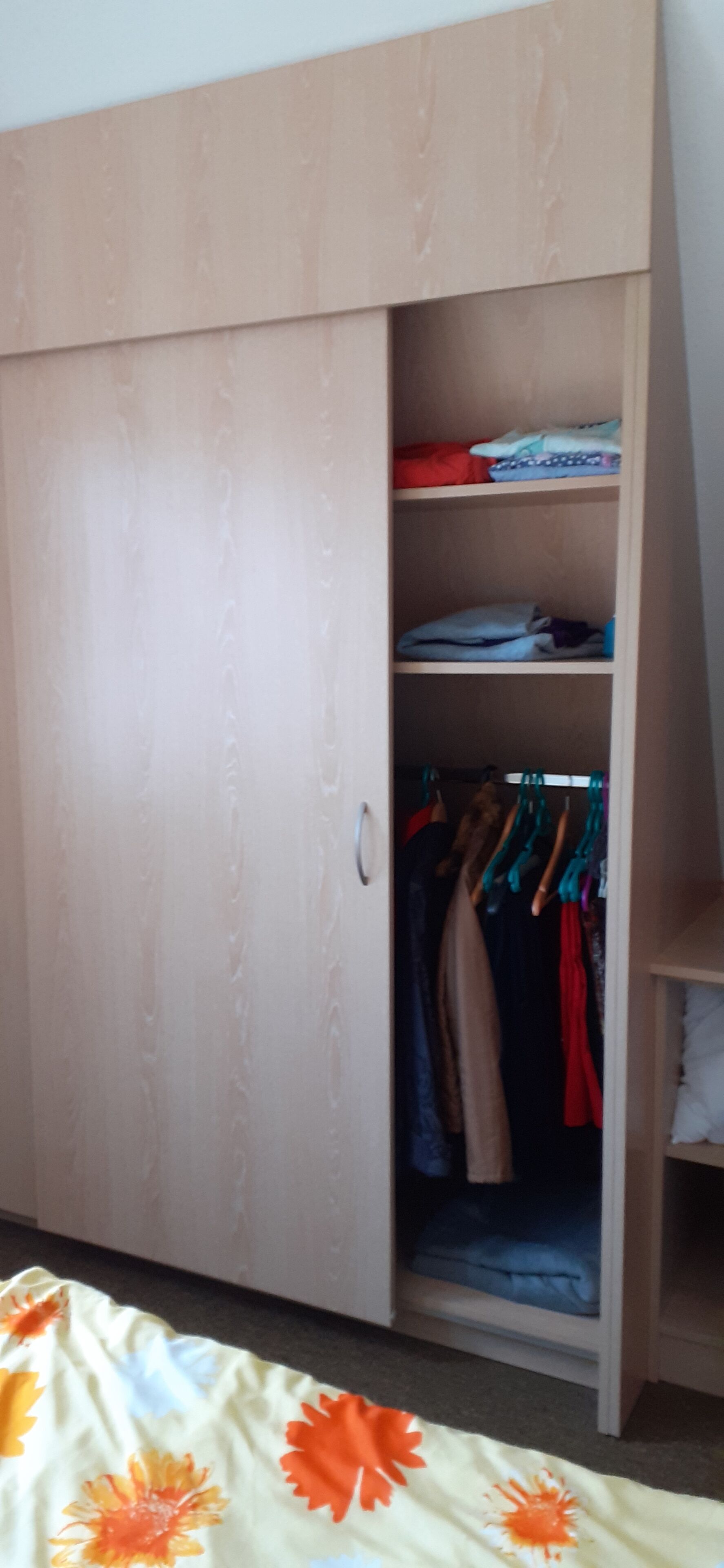 Een garderobe met schuifdeur, planken en kledingroede.