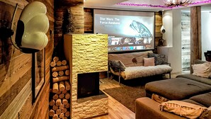 Un salón acogedor con una chimenea de piedra, un sofá cómodo y un televisor que muestra 'Star Wars: El despertar de la Fuerza'.