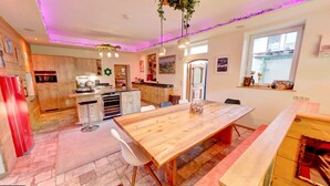 Una cocina moderna con armarios de madera, una isla central y un comedor con mesa y sillas de madera.