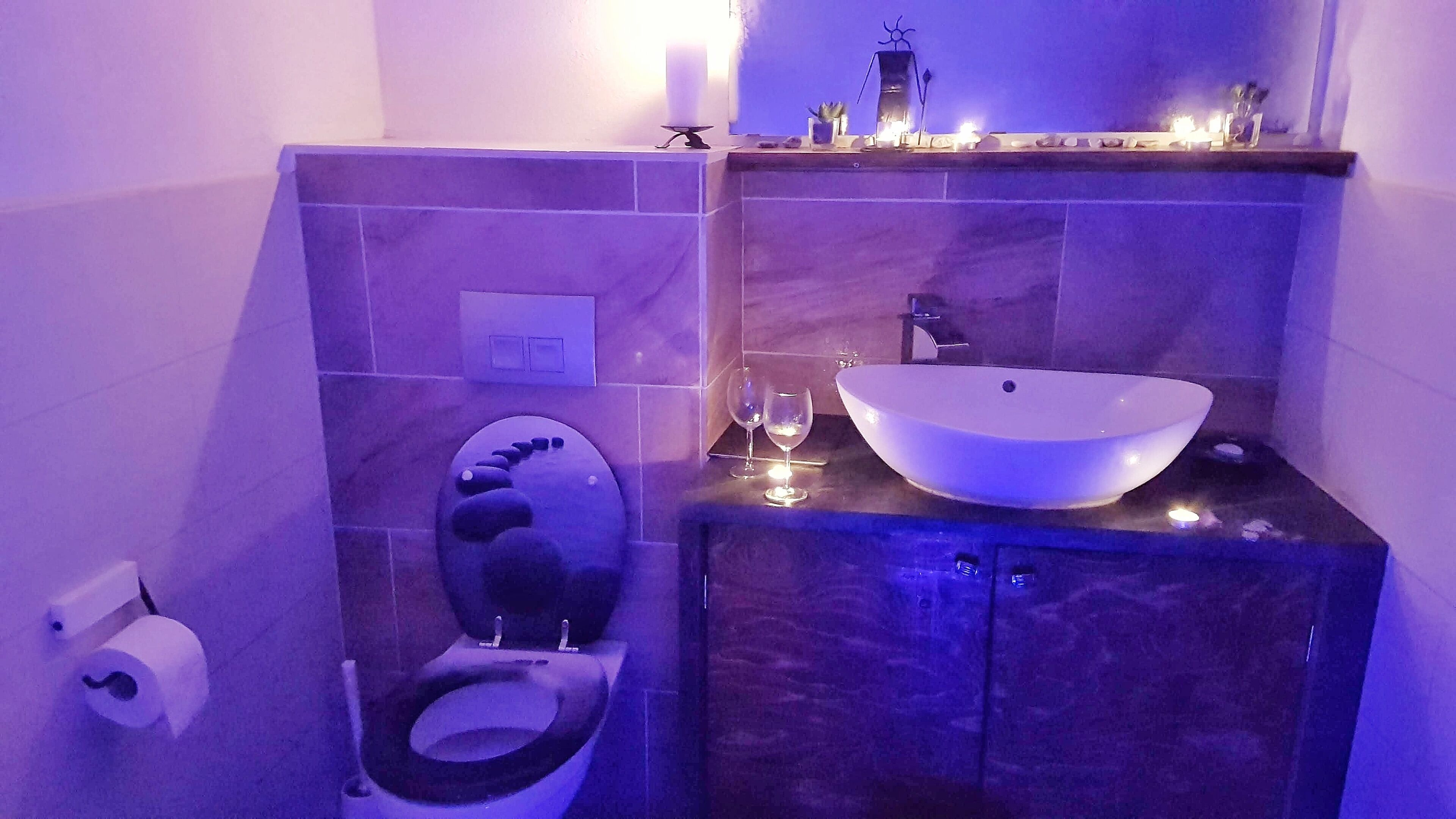 A bathroom with a modern design, featuring a toilet, a sink with a large basin, and a mirror above the sink.