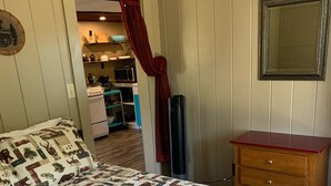 Un dormitorio con colcha acolchada estampada con motivos animales, un aparador de madera y un espejo en la pared.