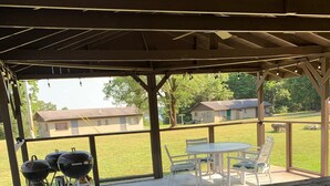 Un espacio de patio cubierto con mesa de picnic y parrilla.