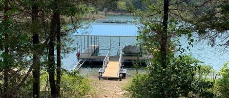 A wooden dock leading to a calm lake surrounded by dense trees.