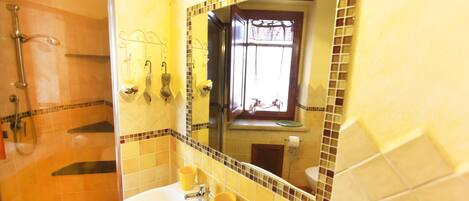 A bathroom with a sink, mirror, and shower.