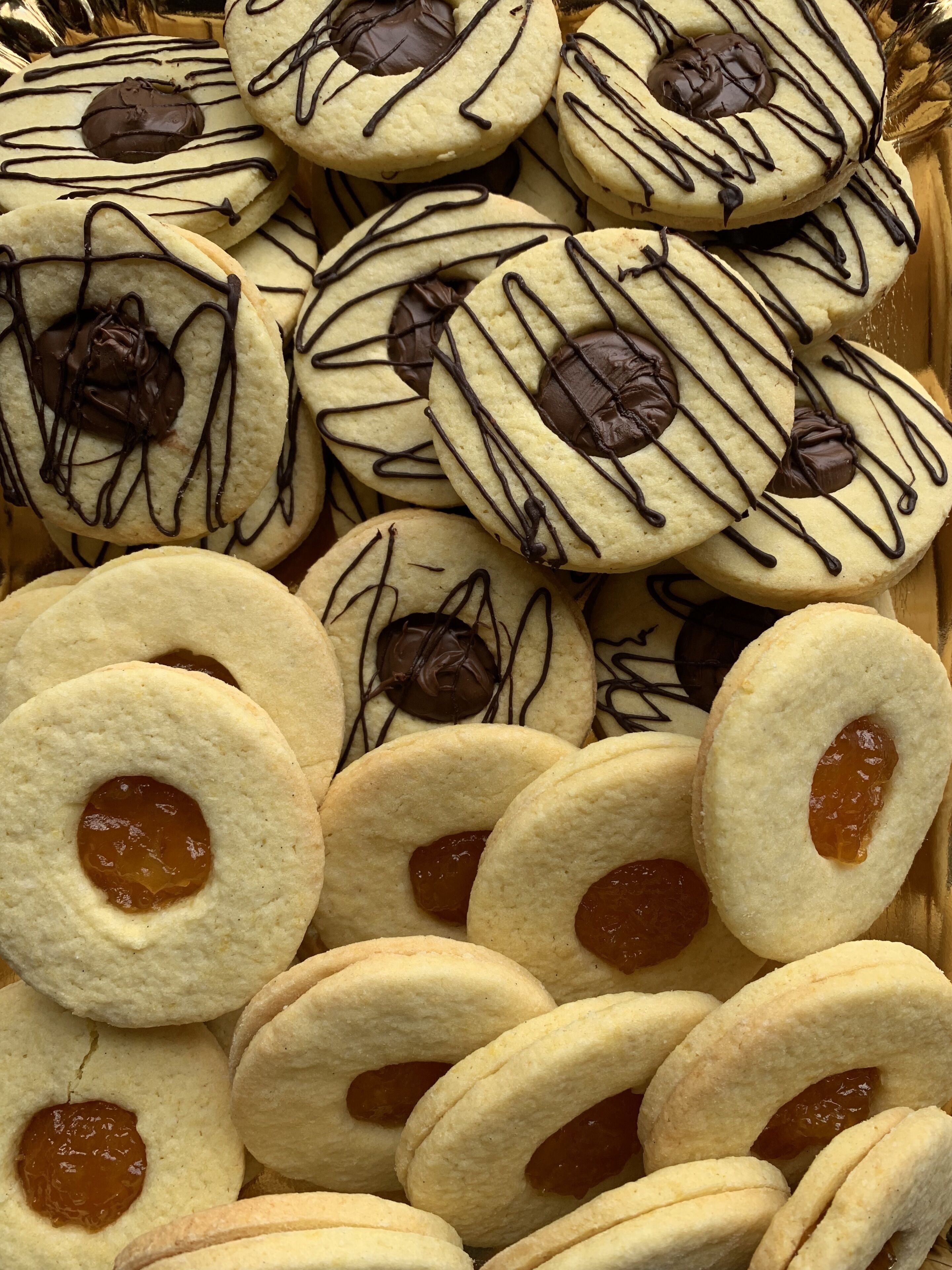 Una cesta llena de galletas de diferentes tipos, algunas con chocolate y otras con mermelada.