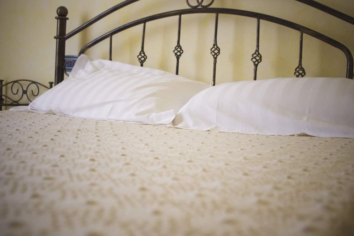 A bed with a metal headboard and white bedding.