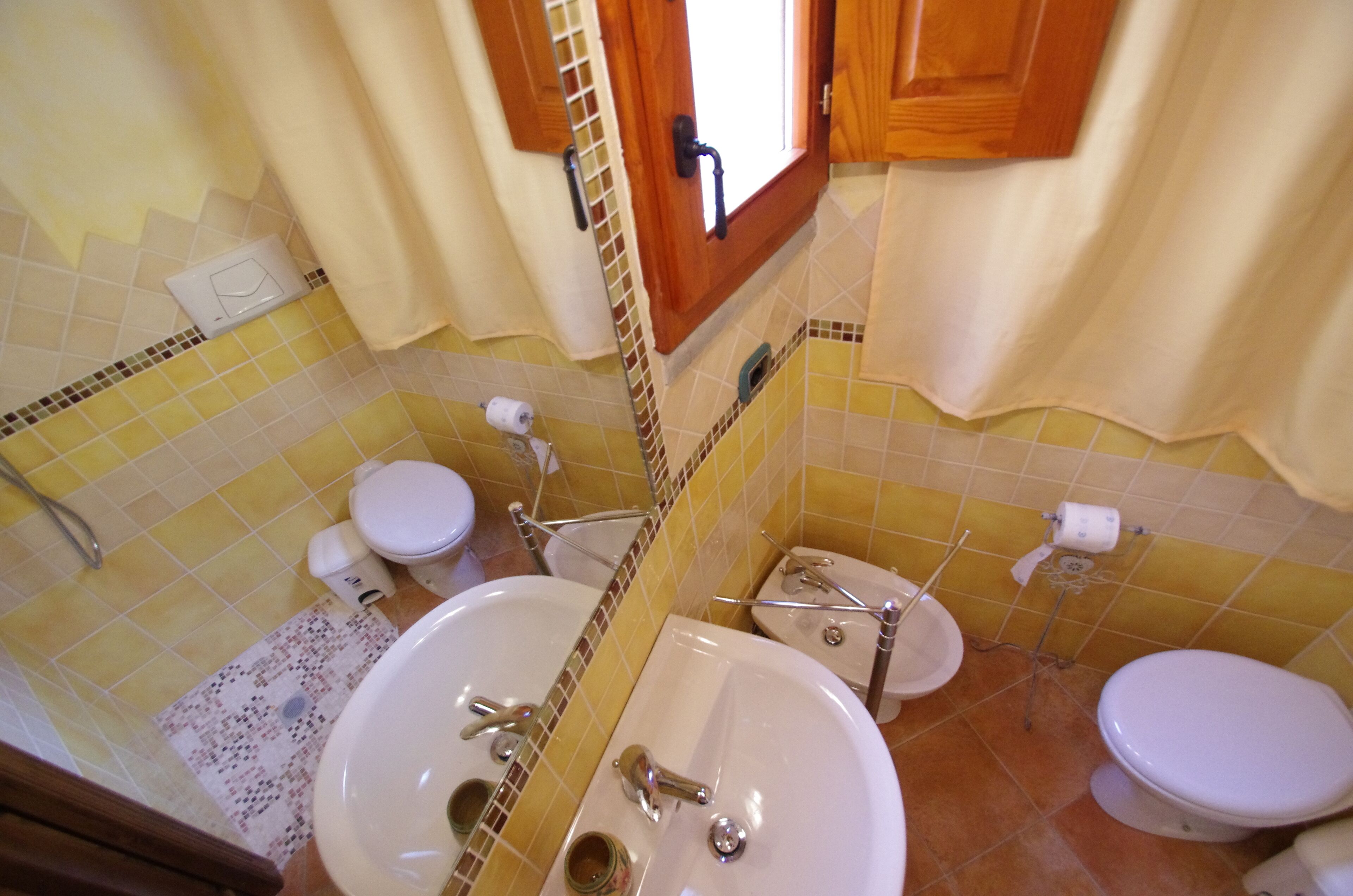 A bathroom with two toilets, a sink, and a shower.