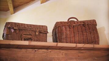 Two wicker baskets on a wooden shelf against a plain wall.