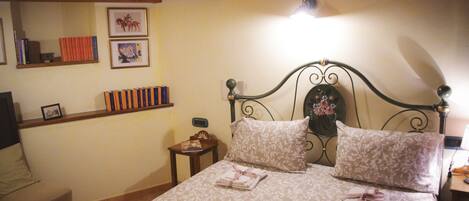 Une chambre à coucher comprenant un lit, une table de chevet, une chaise, une étagère avec des livres et des photos, et un plafond en bois.
