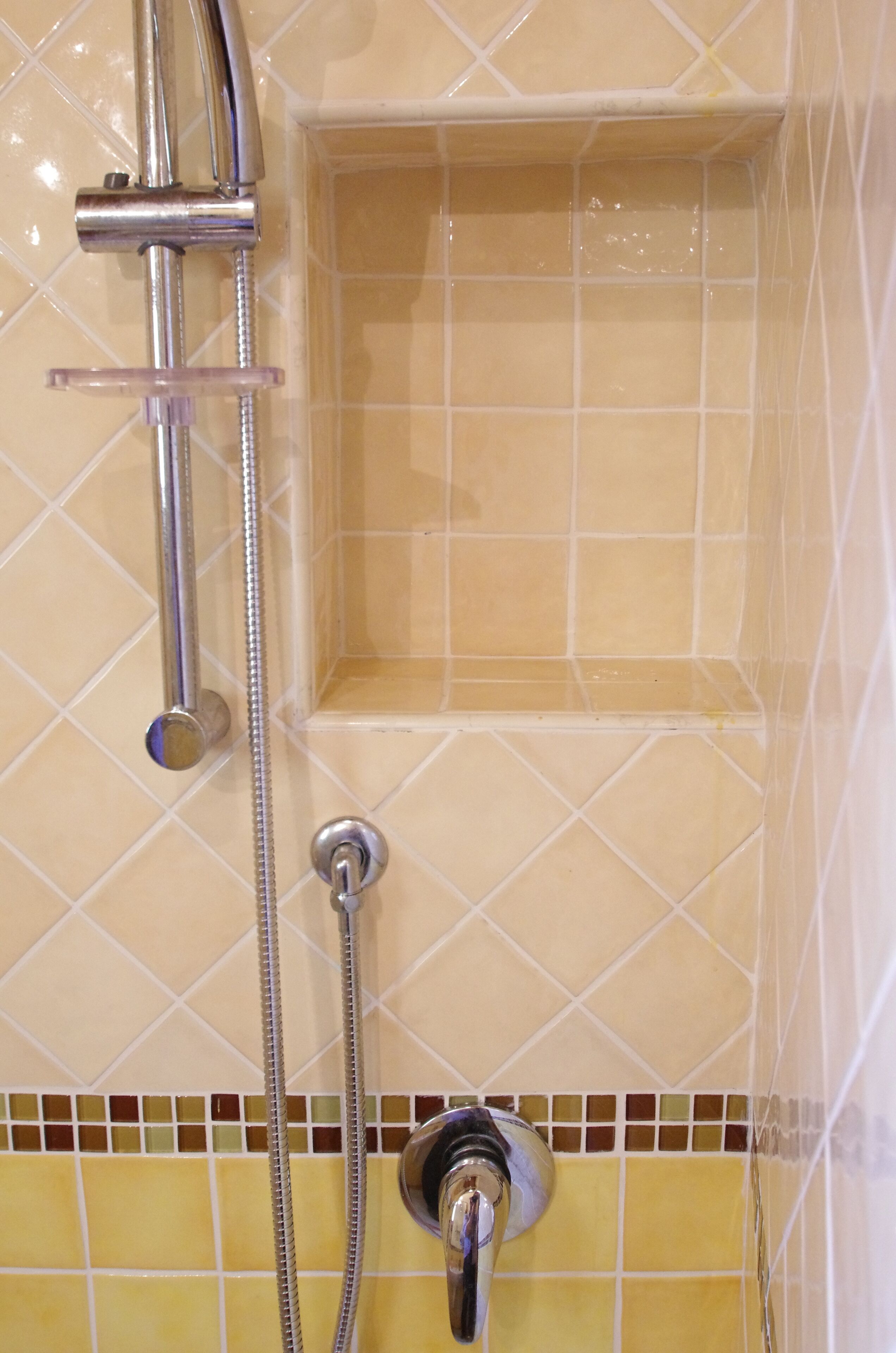 A shower with a handheld showerhead and a fixed wall-mounted faucet.