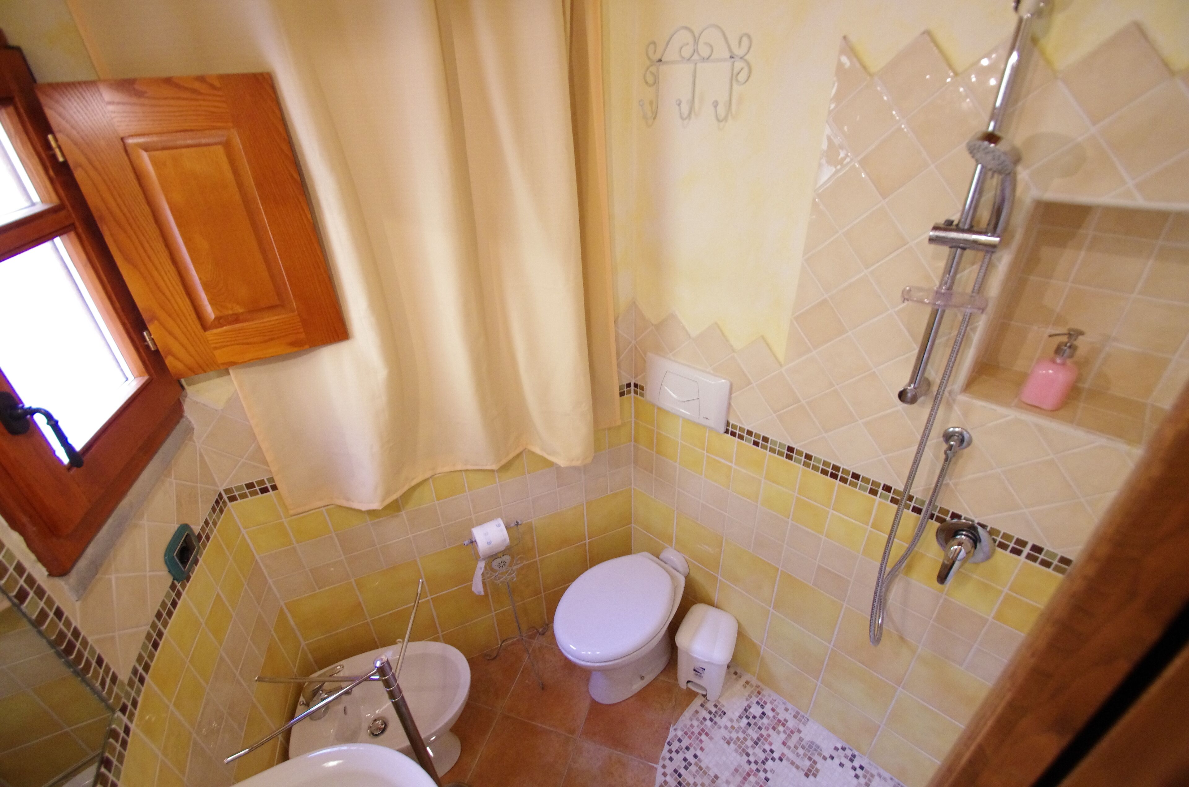 A bathroom with a toilet, a sink, a shower, and a window.