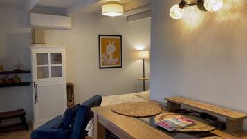 Une pièce chaleureuse comprenant un lit, une table en bois, une lampe et une étagère ornée d’objets décoratifs.