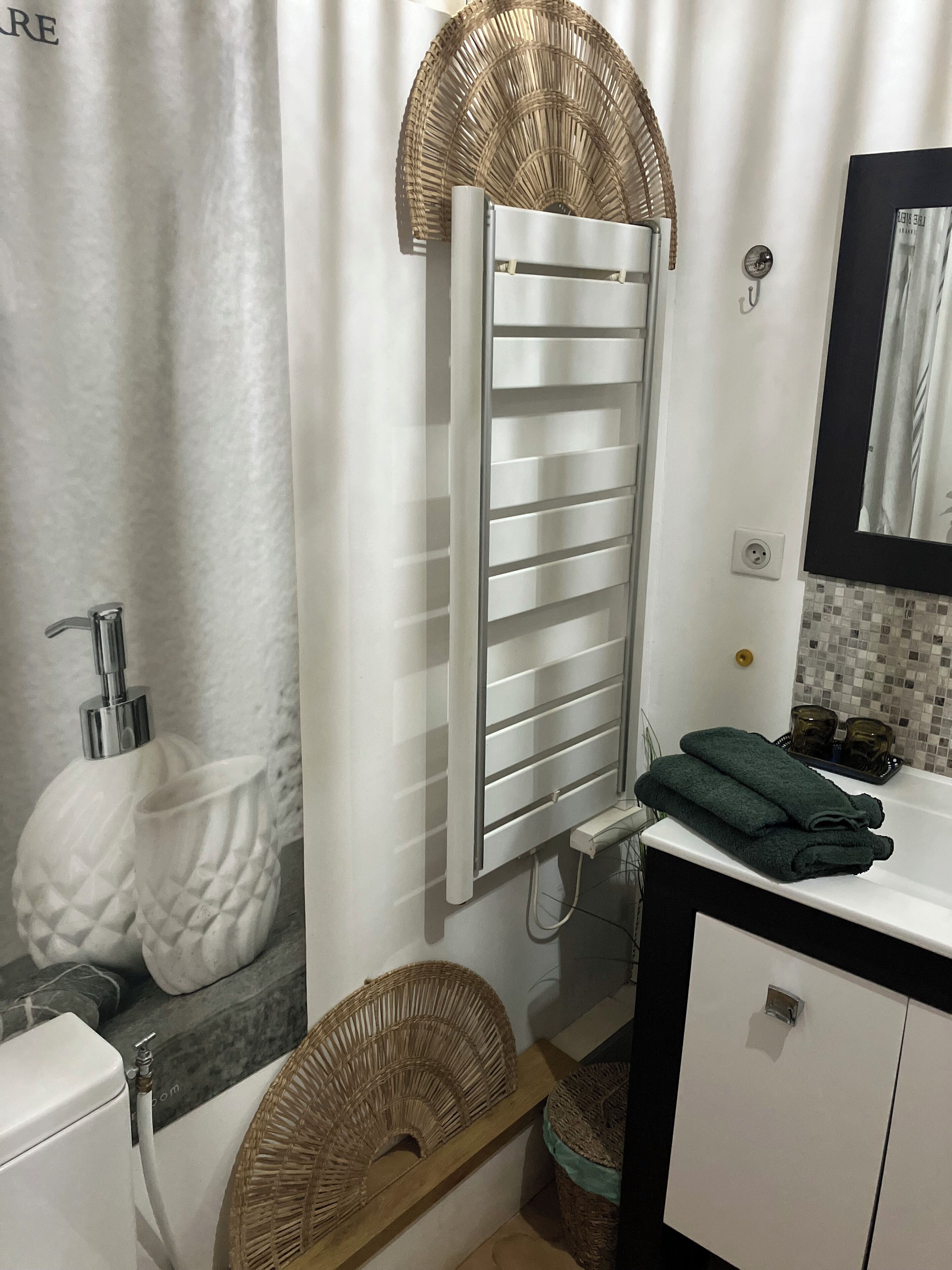 Een badkamer met een wit toilet, een wastafel met spiegel, een handdoekhouder en een douchegordijn.