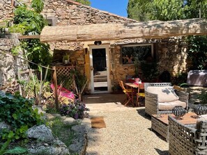 A stone house with a covered patio, outdoor seating, and a garden. - Pretty annex of the mas in the heart of the garrigue of Nîmes (Nimes)