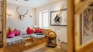 Un salon chaleureux avec un banc en bois, un globe terrestre posé sur un support et une guitare accrochée au mur.