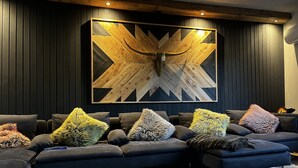 Un salon moderne avec un canapé d’angle, des coussins décoratifs et une grande œuvre d’art murale abstraite en bois.