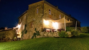 A stone building with a large canopy and a well-lit entrance. - CANONICA 43 Luxury villa in the heart of Tuscany (colle di val d'elsa)