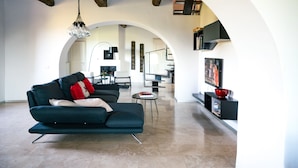 A modern living room with a sofa, a small table, and a TV. There is a bookshelf and a dining area in the background. - CANONICA 43 Luxury villa in the heart of Tuscany (colle di val d'elsa)