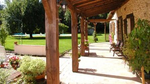 A covered patio area with wooden beams and stone walls, outdoor seating, and potted plants. - Character cottage, large garden and swimming pool, tranquility guaranteed (Sérignac-Péboudou)