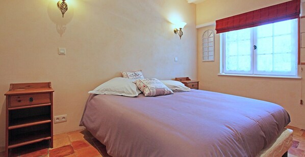 Une chambre à coucher comprenant un lit, des tables de chevet, une commode, une armoire et une fenêtre donnant sur un paysage agréable.