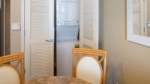 Habitación pequeña con lavadora, una mesa y dos sillas.