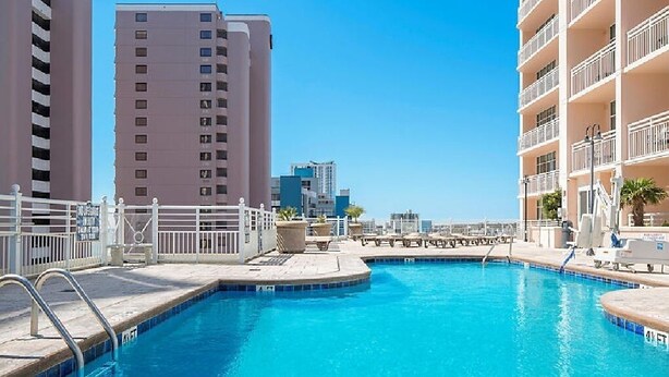Una piscina en la azotea con vista despejada al perfil urbano, rodeada de rascacielos.