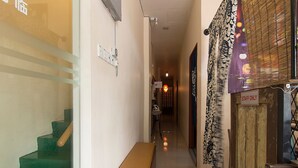 A hallway with a bench, a staircase, and a door with a 'STAFF ONLY' sign. - Oyasumi Hotel (Kulim)