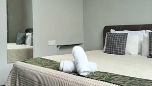 A modern hotel room with a large bed, a mirror, and a small bedside table. - Oyasumi Hotel (Kulim)