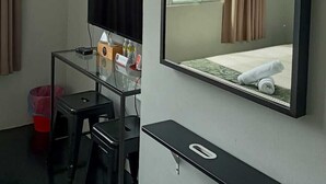 A hotel room with a bed, a TV, a desk, and an air conditioner. - Oyasumi Hotel (Kulim)