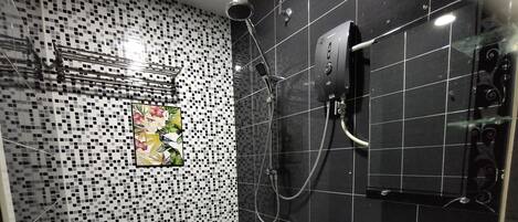 Casa de banho moderna com sanita, chuveiro e lavatório.