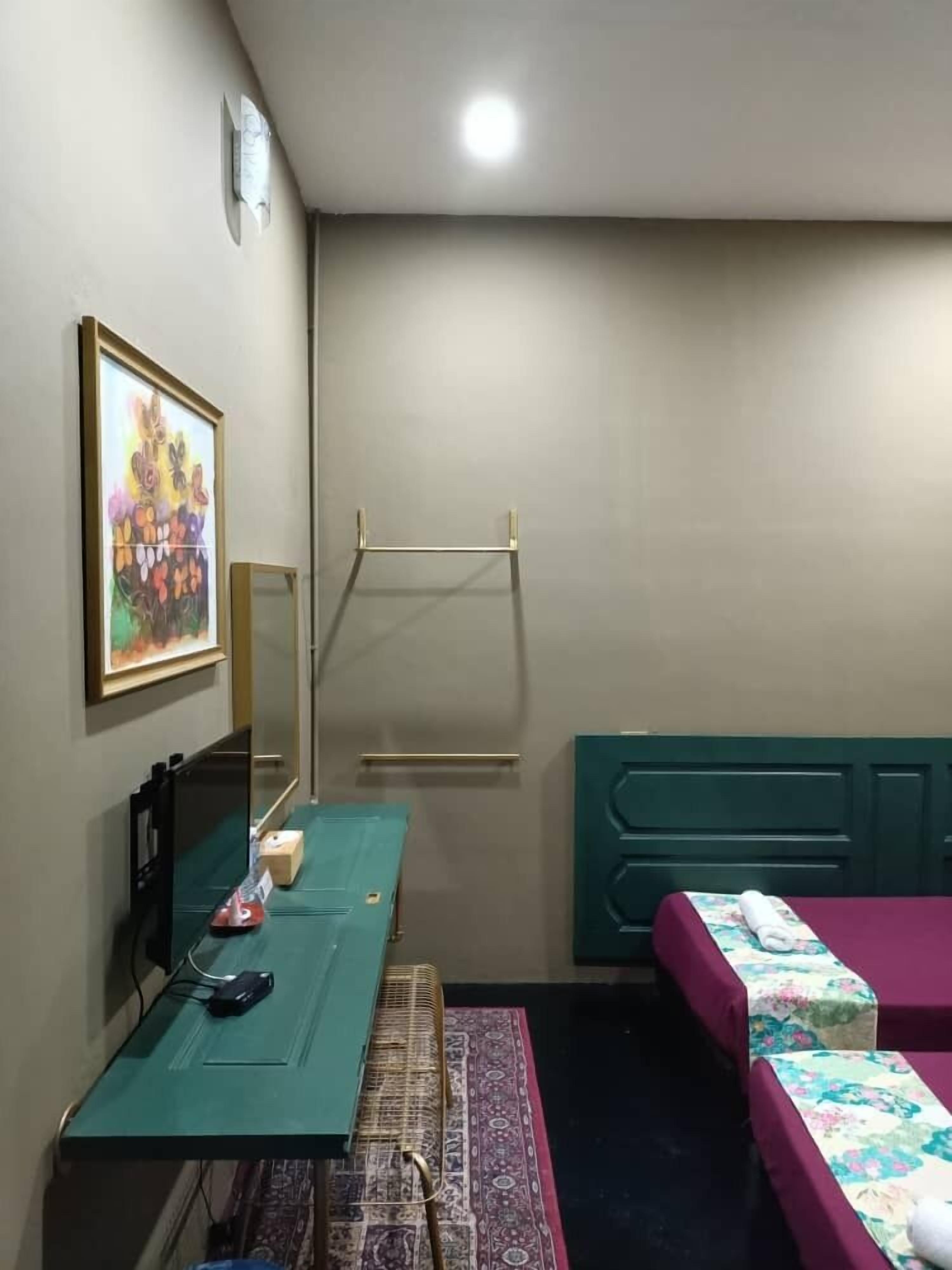 Una habitación pequeña y luminosa con una cama, un escritorio con una computadora, un espejo y un cuadro en la pared.