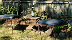 Two metal chairs with cushioned seats and a small table with a bottle and glasses. - 1830s Historic Inn Ithaca NY, Room 8 (Lansing)
